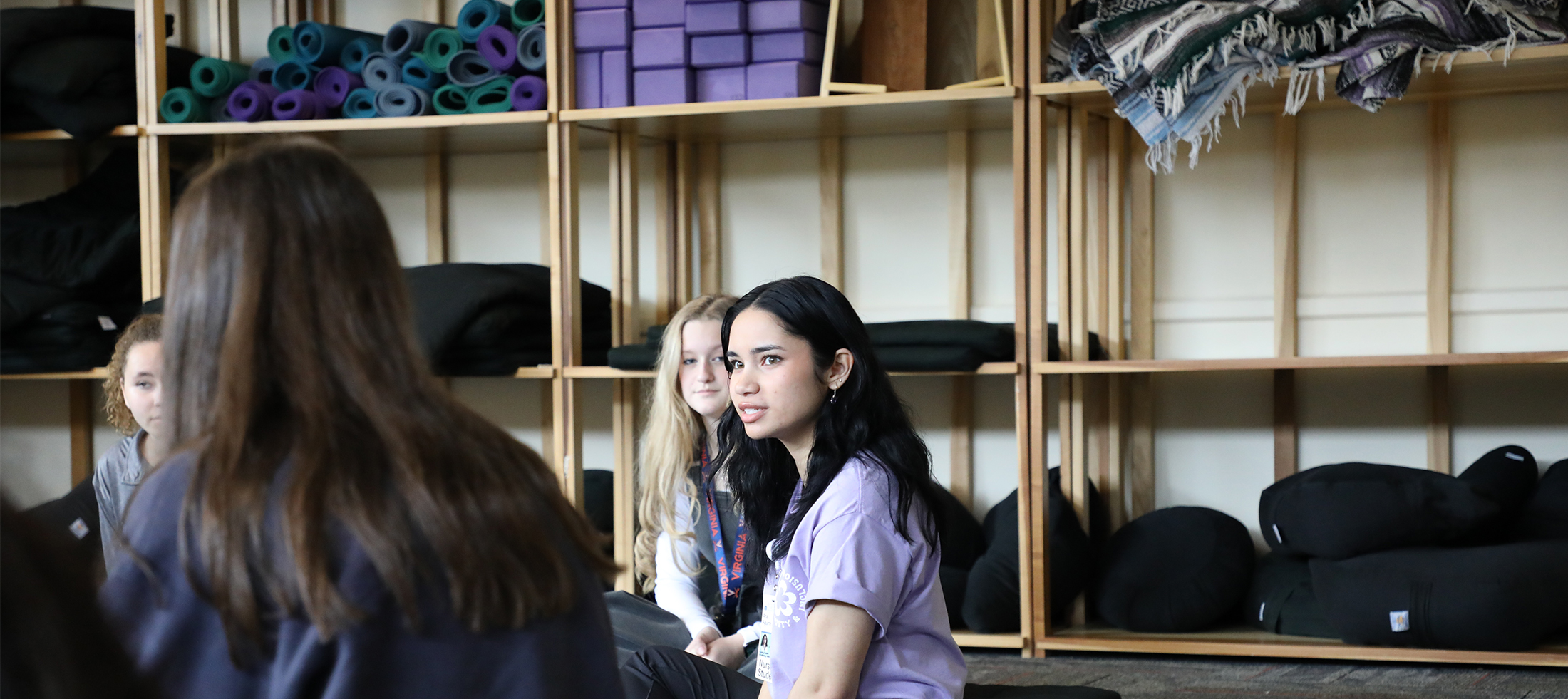 Nursing student leading a conversation with yoga and meditation equipment in the background. 